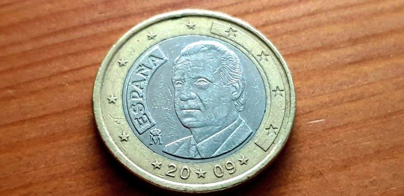 Une pièce de un euro à l'effigie de l'ancien roi d'Espagne Juan Carlos, posée sur une table.